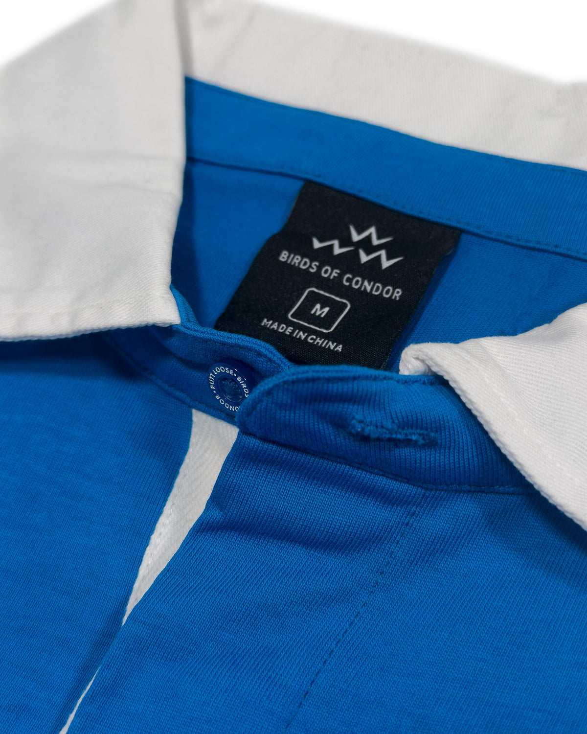 Detail of a blue sweater with a white collar and a hidden button placket.