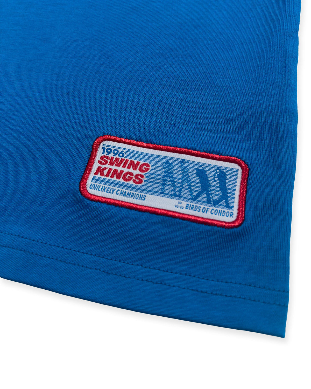 Detail of a blue cotton sweater with a red-bordered embroidered patch featuring golf silhouettes.