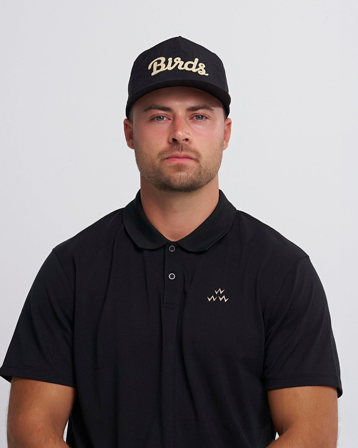 A man wearing a black cap featuring an off white script print and a curved brim.