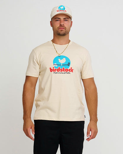 A man wearing a natural t-shirt with a blue and red bird graphic and text.