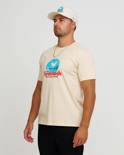 A man wearing a natural t-shirt with a blue and red Birdstock festival graphic print.