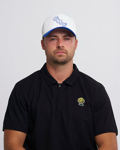 A man wearing a white snapback hat with blue brim and a GOLF text logo on the front.