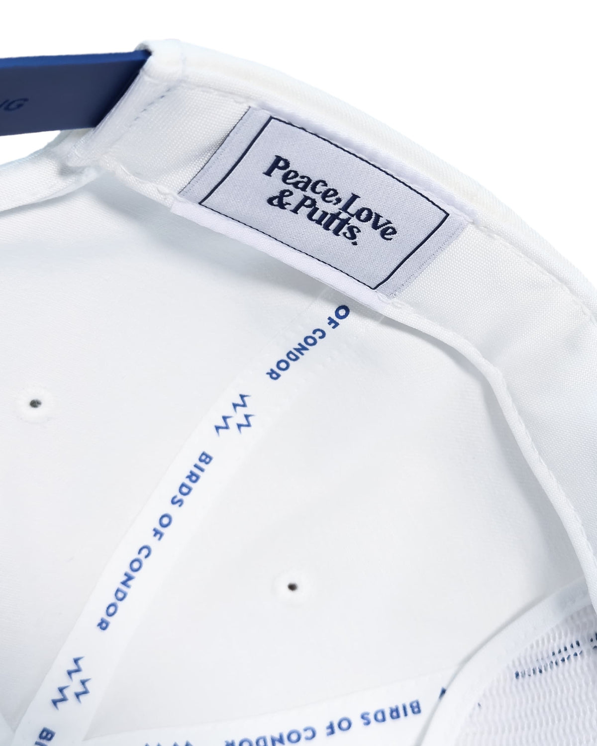 Detail of a white cotton snapback interior showing a woven label reading Peace, Love & Putts and branded taping.