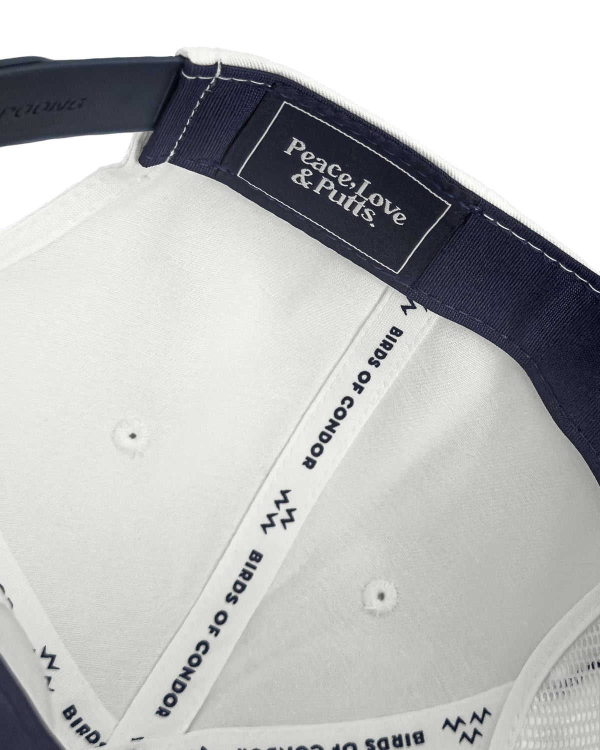 Detail of the inner navy and white snapback cap showing branded taping and an embroidered label.