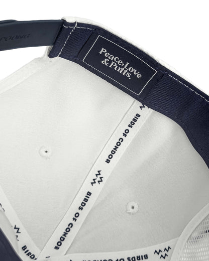 Detail of the inner navy and white snapback cap showing branded taping and an embroidered label.