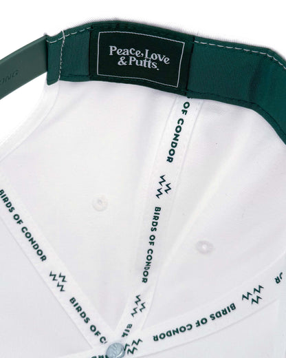 Detail of a white snapback cap showing the interior crown seams with branded taping and a dark green sweatband.
