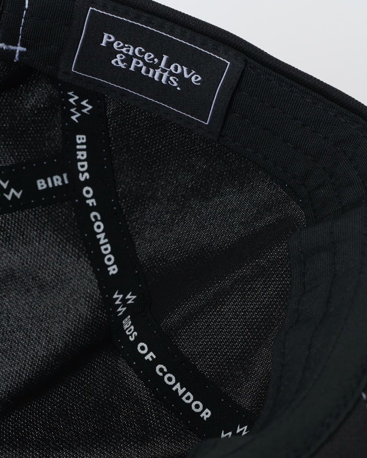 Detail of a black sports cap showing interior seam taping and a branded text label inside the crown.