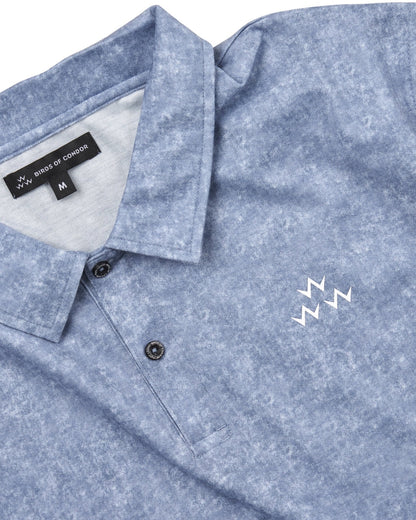 Detail of an acid blue polo shirt with a white triple eagle logo, collar, and tonal buttons.