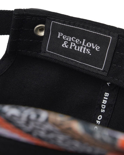 Detail of a black cap with an interior woven label reading Peace, Love & Putts and a patterned brim.