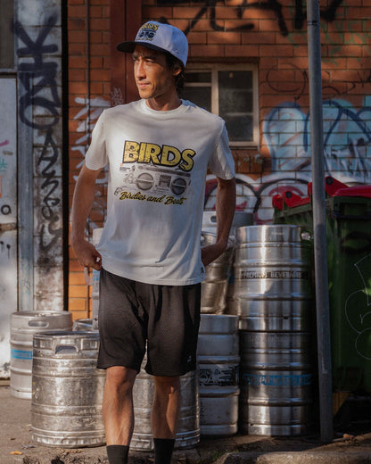 A man wearing a white t-shirt with a retro boombox graphic and yellow Birds and Beats text.