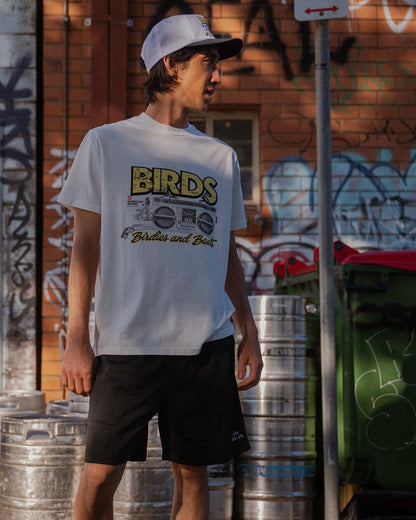 A man wearing a white t-shirt with a retro print featuring a boombox design and text.