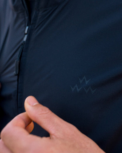 Detail of a black vest featuring a tonal triple eagle print and a full-length zipper with a rubber puller.