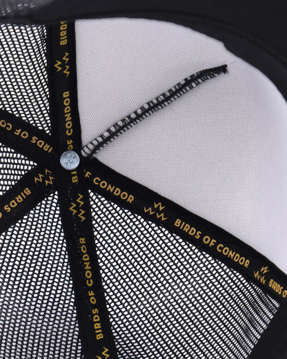 Detail of a black snapback cap showing interior black and gold logo taping.