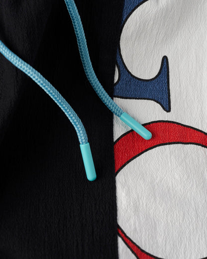Detail of black shorts with light blue drawcords and a white panel featuring a blue and red design.