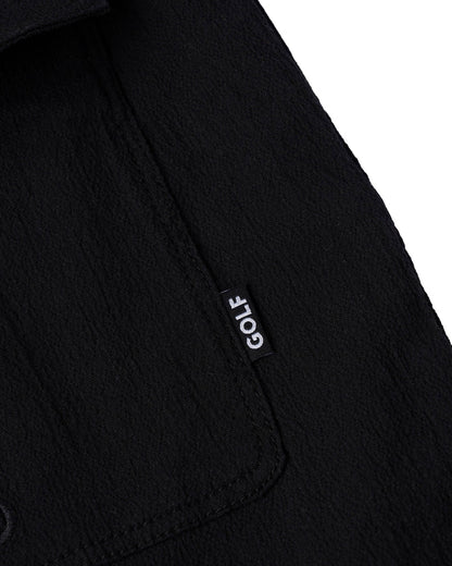 Detail of black shorts showing a side pocket with a small black tag featuring white GOLF text.