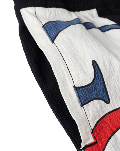 Detail of black shorts featuring white panelled side legs with a multi-coloured graphic design.