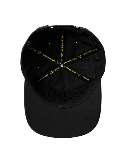 Inside of a black snapback cap featuring yellow logo text printed on the interior seam taping.