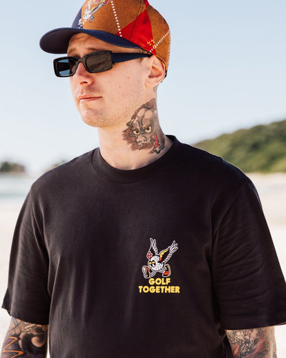 A man wearing a black t-shirt with a small winged golf ball graphic on the chest.
