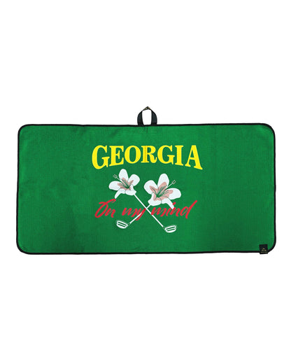 Green golf towel featuring yellow text, crossed flowers, and a red script design with a hanging loop.