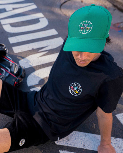 A man wearing a green snapback hat featuring a white globe graphic with multicolored V shapes.