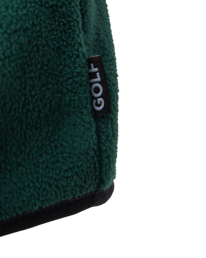 Detail of a dark green fleece jacket showing a small black woven side label with white Golf lettering.