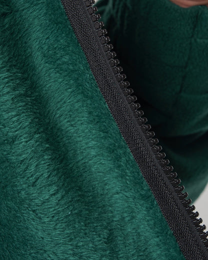 Detail of a dark green fleece sweater featuring a black zipper with teeth.