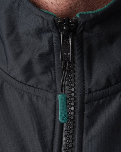 Detail of a dark green fleece sweater collar with black zipper and a green pull tab.