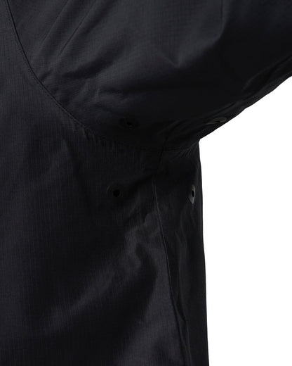 Detail of a black jacket showing underarm eyelet vents and taped seams.