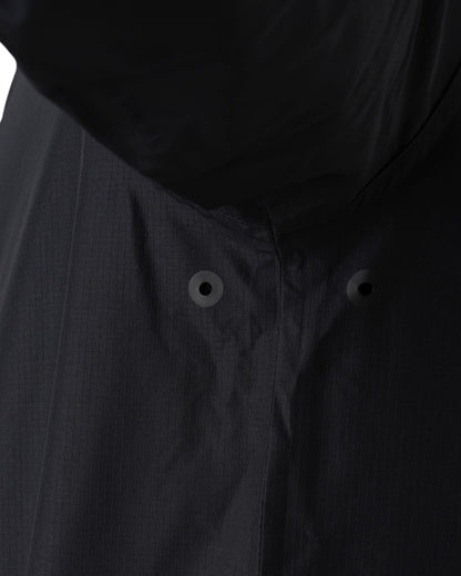 Detail of a black rain jacket featuring underarm metal eyelet vents in the seam.