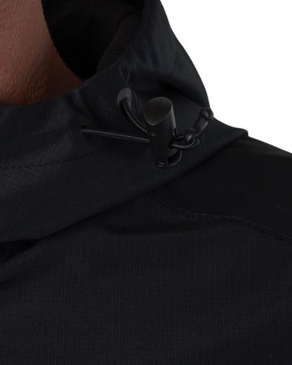 Detail of a black jacket showing the hooded neckline and black drawstring with a plastic toggle.