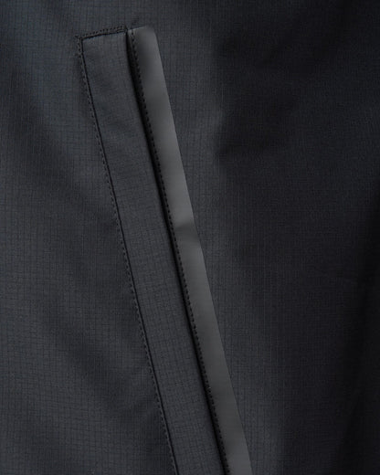 Detail of a black ripstop rain jacket featuring a taped waterproof side pocket zipper.