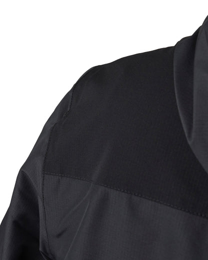 Detail of a black rain jacket featuring a stretch panel across the shoulders and a hood.