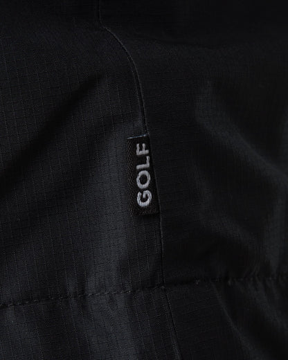 Detail of a black ripstop jacket featuring a vertical black tag with white GOLF text.