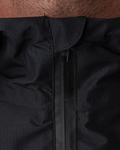 Detail of a black waterproof rain jacket collar featuring a sealed front zipper and hood.