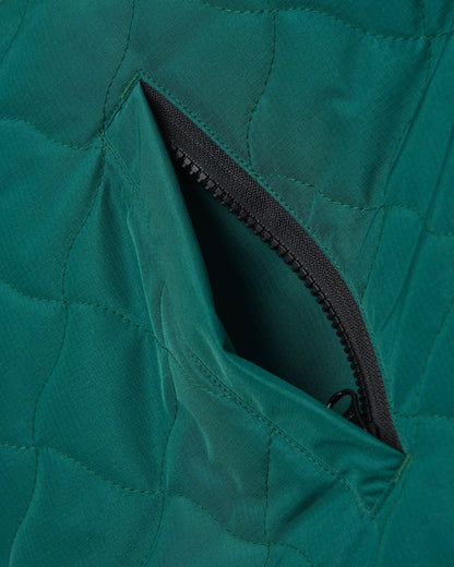 Detail of an amazon green reversible vest featuring warped argyle quilting and a zipped side pocket.