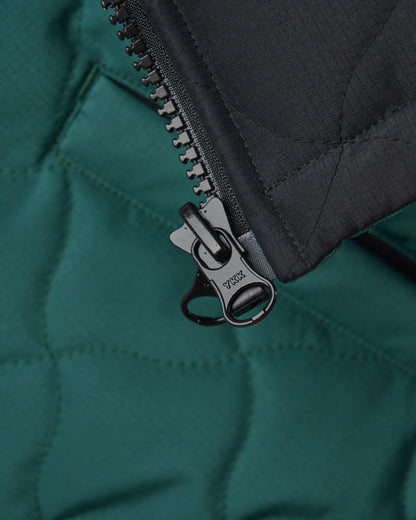 Detail of an amazon green and black reversible vest with warped argyle quilting and a black zipper pull.