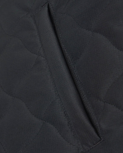 Detail of a black vest with warped argyle quilting and a zippered side pocket.