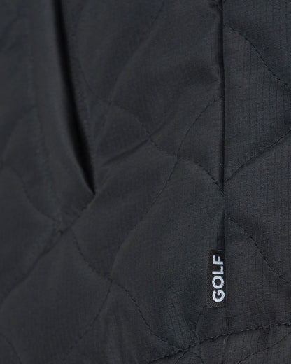 Detail of a black vest with warped argyle quilting, a side pocket, and a small tag reading GOLF.