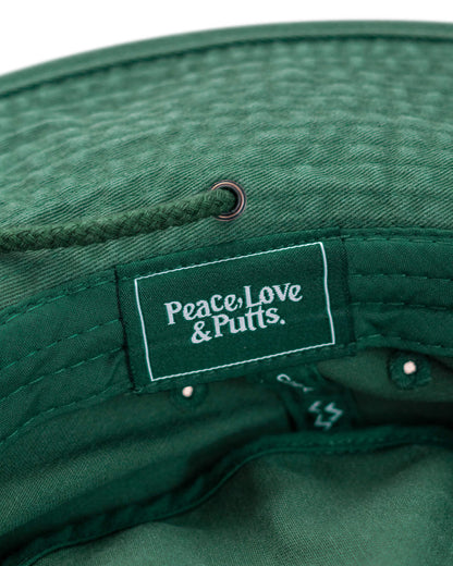 Detail of a green boonie hat featuring a tonal drawcord through a brass eyelet and an interior logo label.