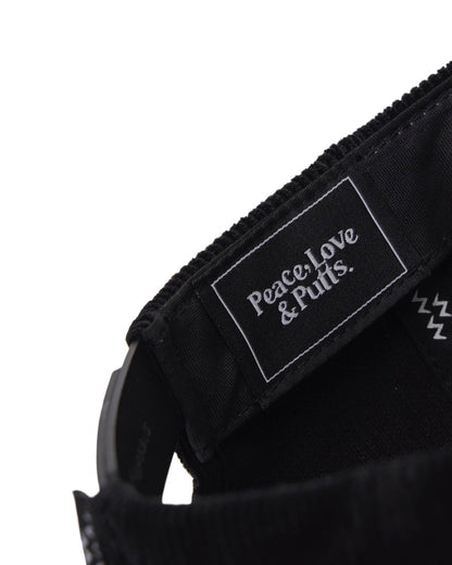 Detail of a black corduroy snapback interior, featuring a branded tag with text and logo.