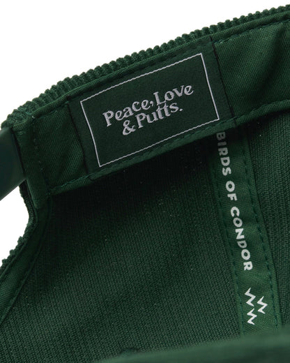 Detail of the interior of an alpine green snapback featuring a white text label reading Peace, Love and Putts.