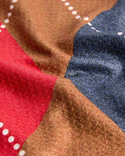 Detail of an argyle golf towel in red, brown, and blue with a textured waffle weave and white dotted argyle lines.