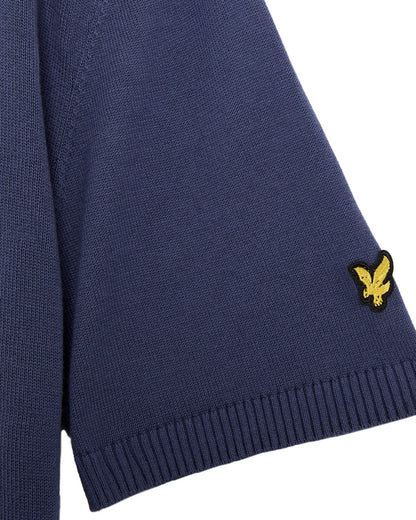 Detail of crown blue cotton polo shirt sleeve with ribbed cuffs and a yellow bird logo.