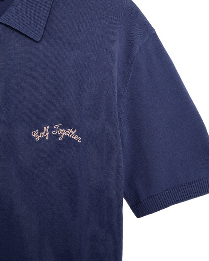 Detail of a crown blue 1/4 zip polo shirt featuring a collar, short sleeves, and chest embroidery.
