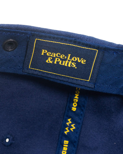 Detail of a navy cap with an embroidered interior label reading Peace, Love & Putts in yellow.