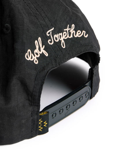 Back of a black nylon snapback featuring embroidered pink script text that reads Golf Together.
