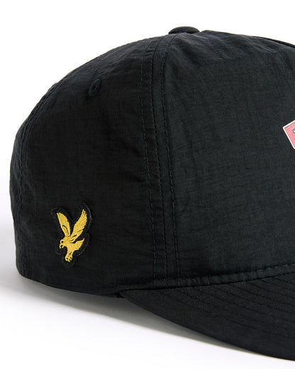 Detail of a black nylon snapback featuring a yellow bird patch on the side and a printed graphic on the front.