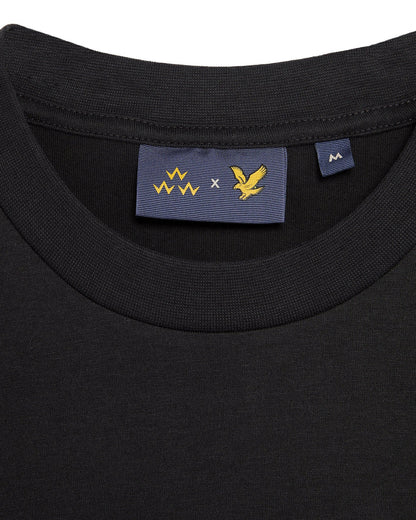 Detail of a black t-shirt with a ribbed crew neck and a blue inner collar label featuring gold logos.