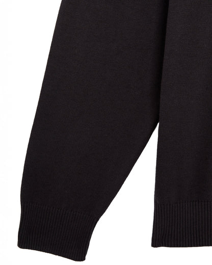 Detail of a phantom black cotton knitted sweater featuring a ribbed cuff and hem.