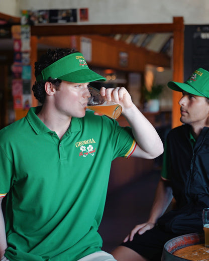 A man wearing a Masters green polo shirt with yellow sleeve trim and a Georgia chest logo.